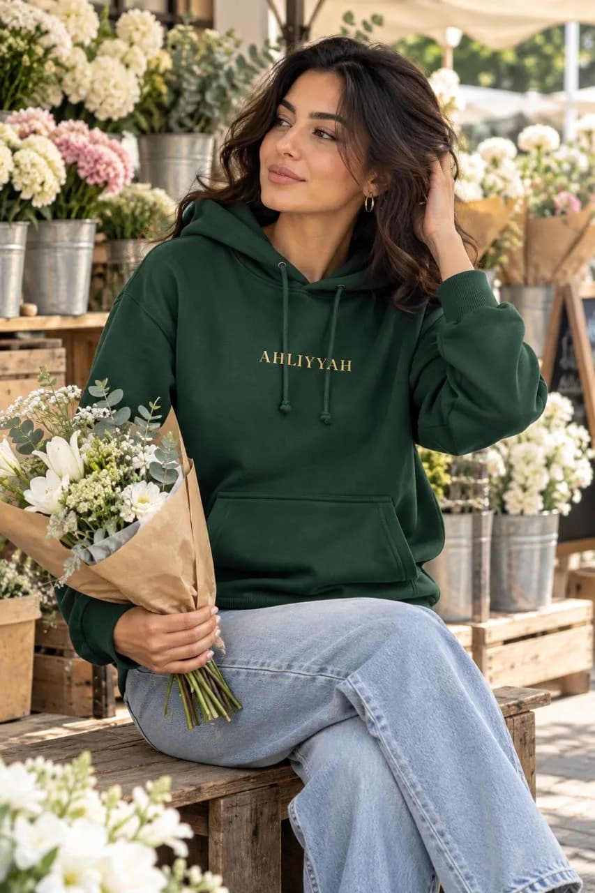 Model in the Forest Green Centenary Hoodie holding flowers